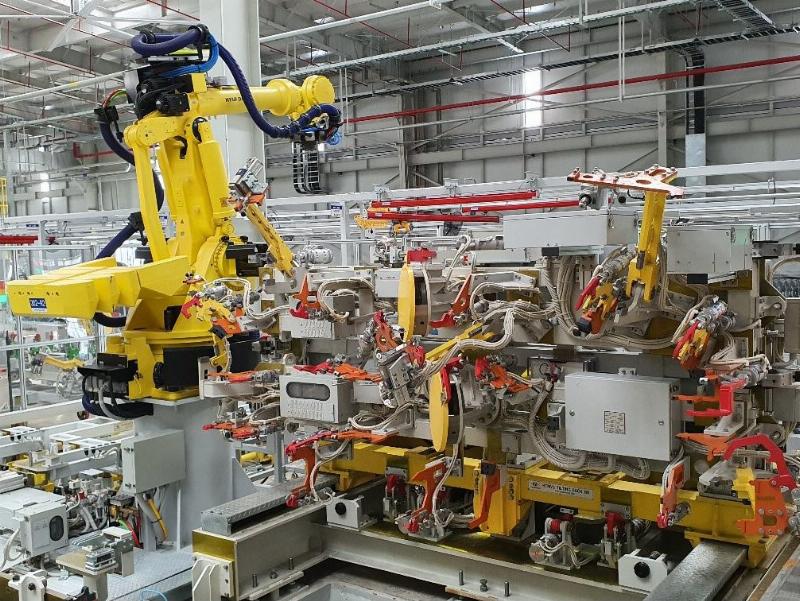 Robot cong nghiep dang thuc hien cong viec han hoac lap rap chinh xac tren day chuyen san xuat tu dong hien dai.